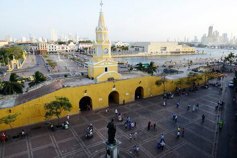 CARTAGENA de INDIAS, COLOMBIA - 28 de enero de 2015: Una vista general de la Puerta del Reloj con la torre del reloj sobre las tres puertas principales que entran en la ciudad vieja visto el 28 de enero de 2015 en Cartagena, Colombia. El horizonte de Cartagena con rascacielos y el puerto se ve al fondo.