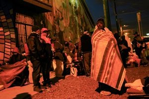 Migrantes , en su mayoría de Venezuela, de pie cubiertos con mantas durante una noche de bajas temperaturas en el centro de El Paso, Texas , EE. UU., 23 de diciembre de 2022. REUTERS/José Luis González