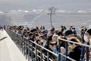 La gente observa un momento de silencio a las 2:46 p. m., el momento en que ocurrió el terremoto en Rikuzentakata, prefectura de Iwate el sábado 11 de marzo de 2023. (Kyodo News via AP)
