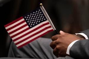 Una persona sostiene una bandera estadounidense en la ceremonia de juramentación como ciudadano de EEUU en Nueva York el 28 de abril del 2021.  (Foto AP/Mark Lennihan)