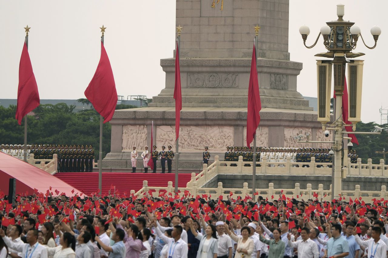 Miembros del partido comunista agitan banderas mientras una guardia de honor se prepara para izar la bandera nacional durante una ceremonia para conmemorar el centenario de la fundación del gobernante Partido Comunista Chino en la Puerta de Tiananmen en Pekín el jueves 1 de julio de 2021. Foto: AP Photo/Ng Han Guan.