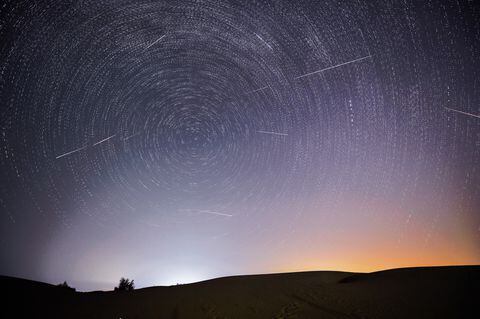 Fotomontaje tomado el 13 de agosto de 2021 que muestra el cielo nocturno durante la lluvia de meteoritos de las Perseidas sobre una zona de demostración ecológica de Engebei en el desierto de Kubuqi, en la Región Autónoma de Mongolia Interior, en el norte de China.
