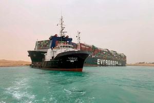 En esta imagen publicada por la Autoridad del Canal de Suez, un barco navega ante un enorme carguero llamado Ever Green, varado el miércoles 24 de marzo de 2021 tras quedarse atravesado en el Canal de Suez, Egipto, y bloquear un paso marítimo crucial para el tráfico global de mercancías. (Autoridad del Canal de Suez via AP)