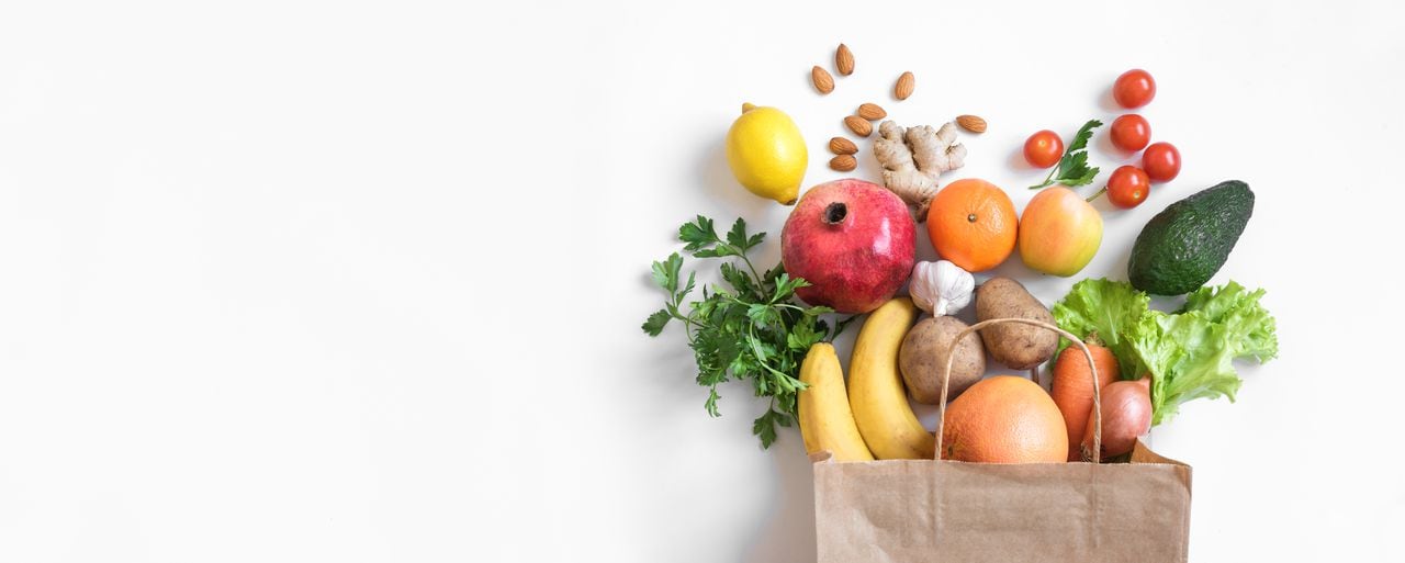 Fondo de alimentos saludables. Comida vegetariana vegana saludable en verduras y frutas de bolsa de papel en blanco, espacio de copia, banner. Supermercado de alimentos de compras y concepto de alimentación vegana limpia.