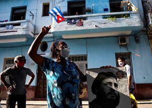 An elderly woman waves a Cuban flag holding a poster of Cuban late leader Fidel Castro in Havana, on July 26, 2021. - The Cuban government on July 26 will commemorate the 68th anniversary of the guerrilla assault on the Moncada Barracks, widely regarded as the beginning of the Cuban Revolution. (Photo by YAMIL LAGE / AFP)