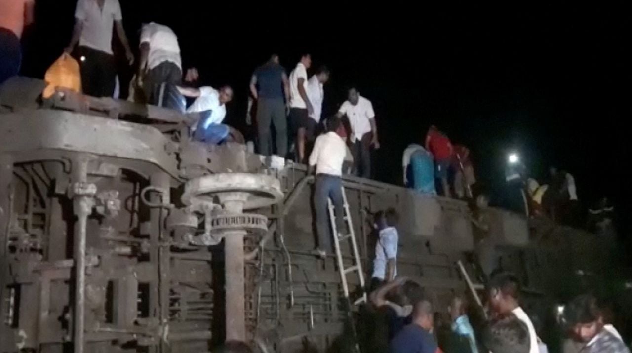 Las personas intentan escapar de los compartimentos volcados, luego de la colisión mortal de dos trenes, en Balasore, India, el 2 de junio de 2023