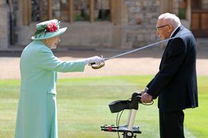 (FILES) In this file photo taken on July 17, 2020 Britain's Queen Elizabeth II uses the sword that belonged to her father, George VI as she confers the Honour of Knighthood on 100-year-old WWII veteran Captain Tom Moore at Windsor Castle in Windsor, west of London on July 17, 2020. - Britain's lockdown hero, Captain Tom Moore has died at the age of 100 after testing positive for Covid-19.  The charity fundraiser was taken to Bedford Hospital on Sunday after testing positive for coronavirus last week. (Photo by Chris Jackson / POOL / AFP)