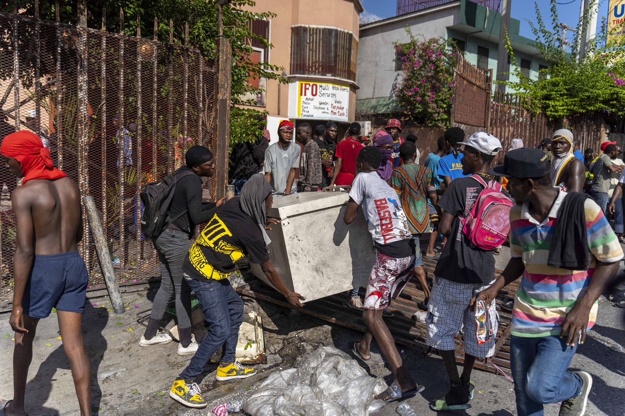 Los hombres huyen con bienes saqueados durante una protesta contra el primer ministro haitiano Ariel Henry pidiendo su renuncia, en Port-au-Prince, Haití, 10 de octubre de 2022. - Las protestas y los saqueos han sacudido el ya inestable país desde el 11 de septiembre, cuando el primer ministro Ariel Henry anunció un aumento en el precio del combustible. (Foto de Richard Pierrin / AFP)