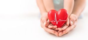 Un adulto, una madre y un niño sostienen un corazón rojo en sus manos. Concepto de caridad, seguro de salud, amor, día internacional de cardiología.