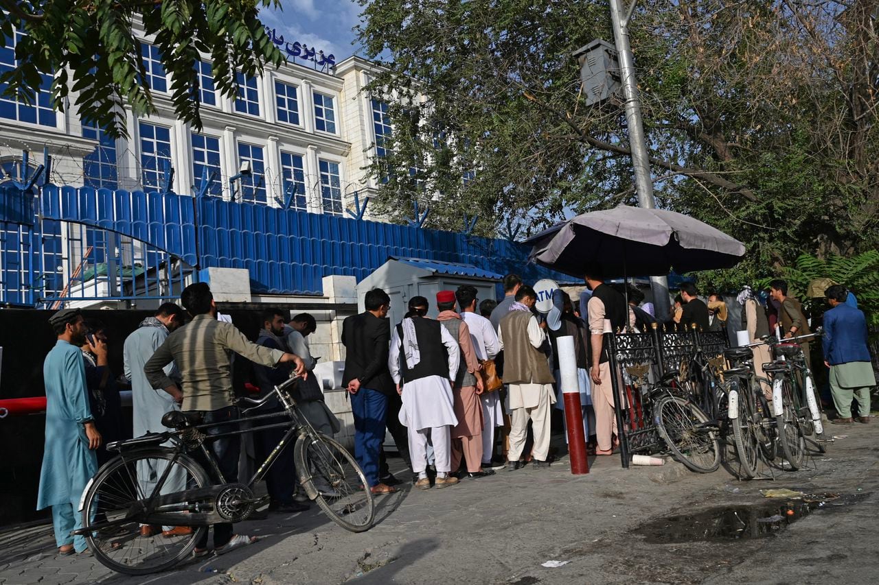 Los afganos hacen cola mientras esperan su turno para cobrar dinero de un cajero automático frente a un banco a lo largo de una carretera en Kabul el 21 de agosto de 2021, días después de la impresionante toma de Afganistán por los talibanes. (Foto por - / AFP)