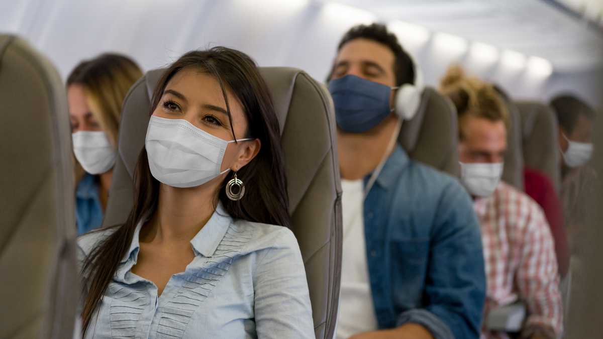 Retrato de una mujer latinoamericana que viaja en avión con mascarilla durante la pandemia de COVID-19.