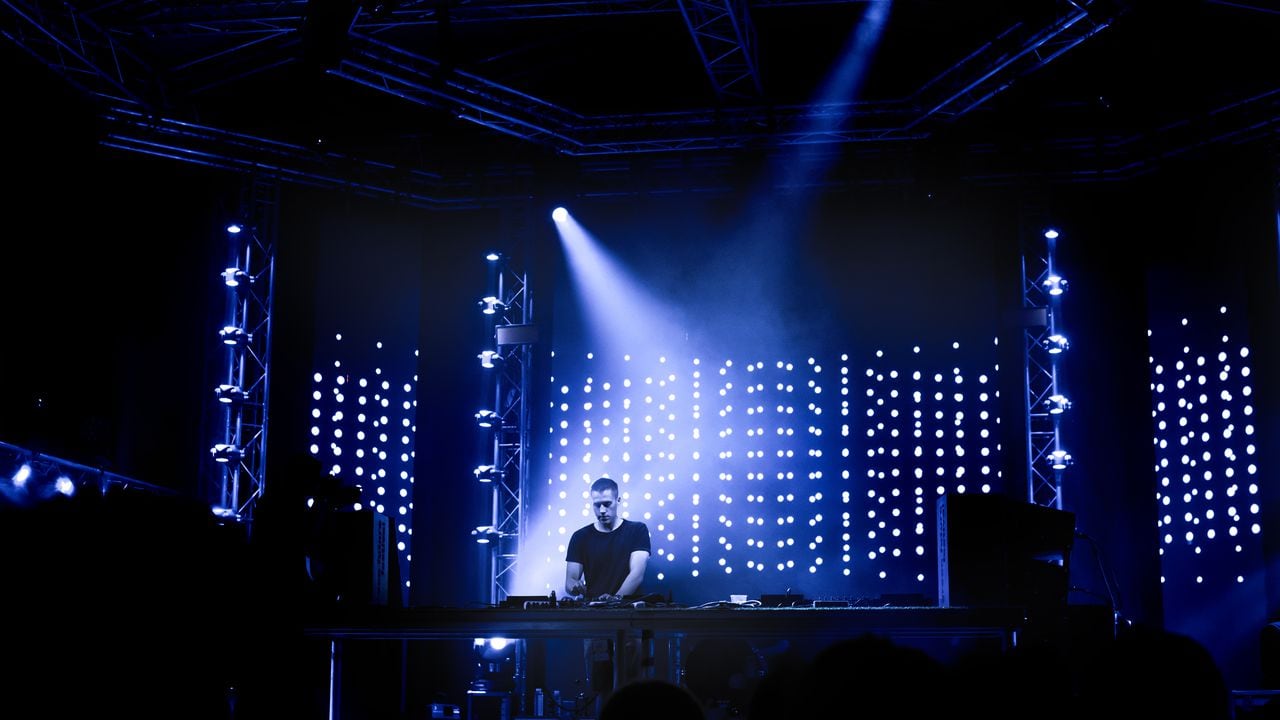 Dj playing techno music on the stage during night concert.