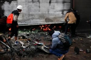 Supermarket workers inspect the fire damage after clashes erupted between riot police and anti-government protesters in Puno, Peru, on January 9, 2023. - At least 12 people died Monday in Peru as anti-government protesters trying to overrun an airport clashed with security forces, officials said. The violence took place in the southeastern city of Juliaca, in the Puno region, an official in the local ombudsman's office told AFP. (Photo by Juan Carlos CISNEROS / AFP)