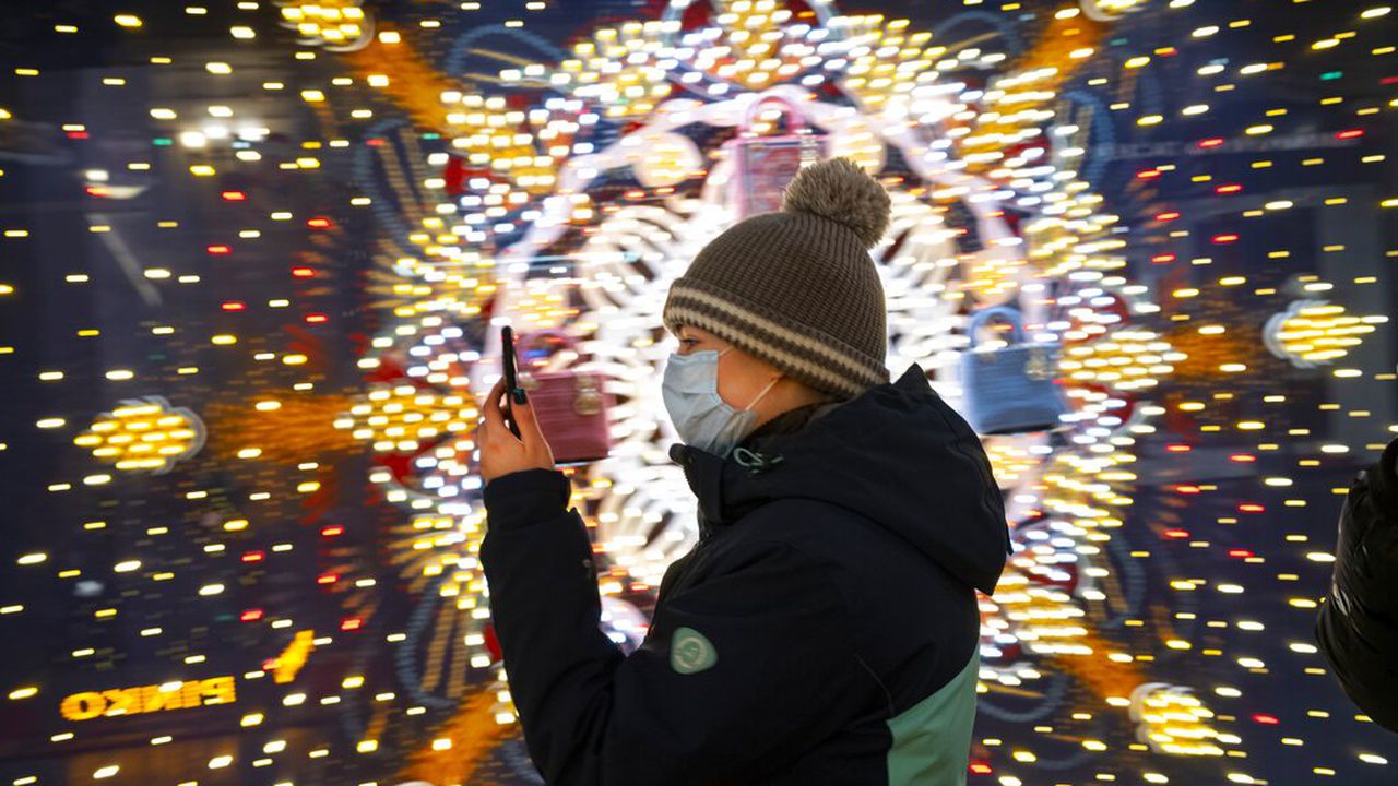 A visiter wearing a face mask to help curb the spread of the coronavirus looks at her smartphone as she walks in the GUM State Department store decorated for Christmas and New Year celebrations virtually empty due to the coronavirus pandemic in Moscow, Russia, Thursday, Dec. 3, 2020. Russia's coronavirus vaccine Sputnik V will be available for people in high-risk groups at 70 medical facilities in Moscow starting on Saturday. According to Moscow Mayor Sergei Sobyanin, those working in education and medical facilities, along with municipal workers, can get the shots. (AP Photo/Alexander Zemlianichenko)