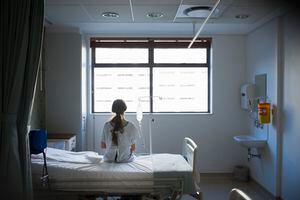 Patient sitting on hospital bed waiting for surgery looking out window