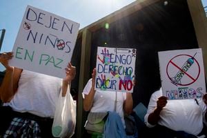 Las personas sostienen carteles que dicen "Deje a los niños solos" y "Tengo derecho a decir que no" durante una manifestación contra la vacunación obligatoria contra el COVID-19 para niños en San José, el 5 de enero de 2022. (Photo by Ezequiel BECERRA / AFP)
