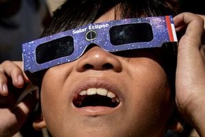 Un niño mira el eclipse solar híbrido con gafas protectoras, en Marikina City, Metro Manila, Filipinas, 20 de abril de 2023. 