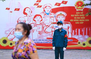 A masked security person guards outside a polling station in Hanoi, Vietnam Sunday, May 23, 2021. Vietnamese cast their ballots to elect 500 delegates for a five-year term at the National Assembly, Vietnam's legislative body, as the country is combating a new wave of COVID-19. (AP Photo/Hau Dinh)