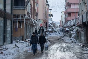 La gente camina con bolsas de plástico en la calle junto a edificios destruidos tras un terremoto mortal en Elbistan, Turquía, el 14 de febrero de 2023. 