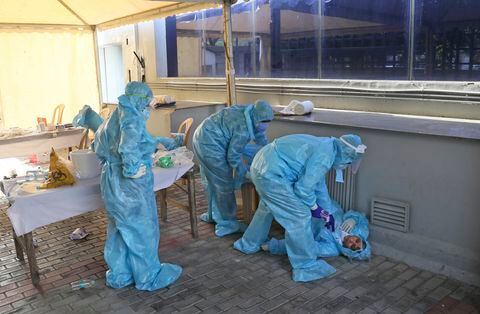 Trabajadores de salud atienden a un colega que se desmayó a causa de fatiga y horas largas de trabajo en un centro de diagnóstico de covid-19 en New Delhi, India
