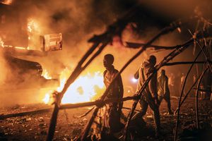 Personas caminan junto a vehículos de la ONU que fueron incendiados en Goma, República Democrática del Congo, el martes 1 de noviembre de 2022.