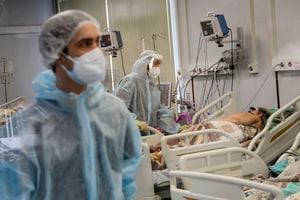 Personal sanitario, vestidos con trajes especiales, tratan a enfermos de COVID-19 en la UCI del Hospital de Infecciones número 23 de Nizhny Novgorod, Rusia, el 20 de octubre de 2021. (AP Foto/Roman Yarovitcyn)
