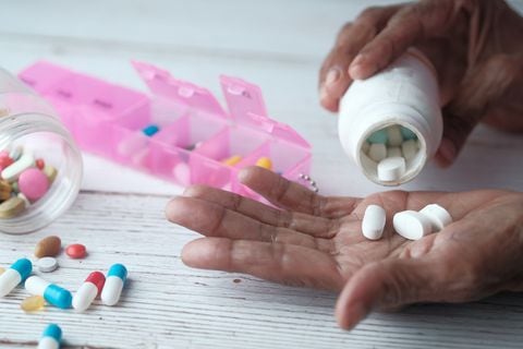 Anciana vertiendo pastillas de botella en mano, vista superior