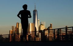 El sol se pone en el horizonte del bajo Manhattan y el One World Trade Center en la ciudad de Nueva York mientras una persona trota a lo largo del río Hudson el 31 de agosto de 2023, en Jersey City, Nueva Jersey. (Foto de Gary Hershorn/Getty Images)