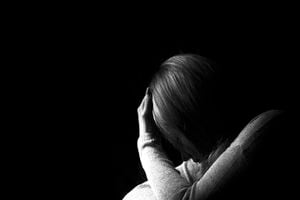 Black and white portrait of a woman hiding her face with hands. Stop violence against woman or mental health concept. Studio shot.