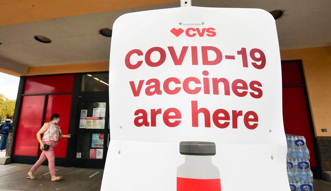 Una señora ingresa a un centro de vacunación con un aviso que lee "Vacunas de covid-19 aquí" en Monterey Park, California, 27 de abril 2021