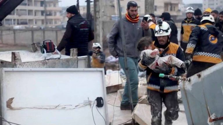 Un rescatista lleva a un niño herido lejos de los escombros en Siria.