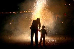 Mpd 5157: A father and son bursting fire crackers while celebrating Diwali, the festival of lights at the marine drive in south Bombay now Mumbai, Maharashtra, India. 