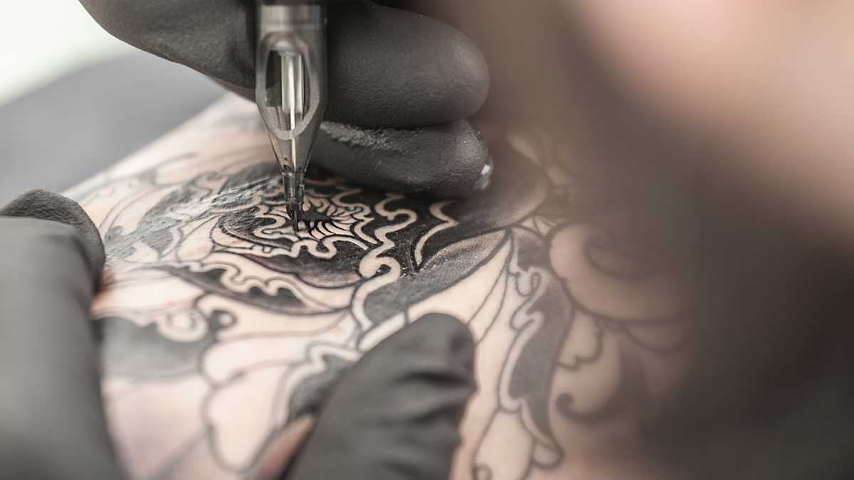 Tattooist drawing on arm of client