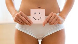 Primer plano de mujer joven sosteniendo papel con marca de sonrisa sobre su estómago. Concepto de educación sexual de higiene de la salud.