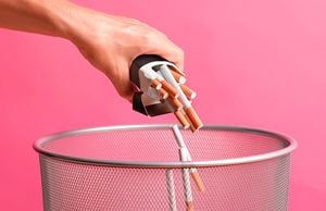 Close up of a woman throwing a pack of cigarettes away in a bin