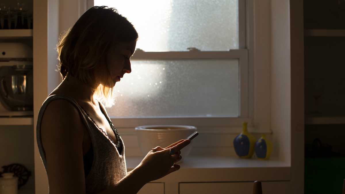 Silhouette of young woman looking at smart phone