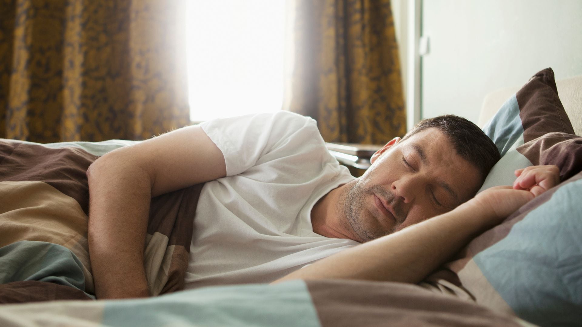 Hombre durmiendo en la cama mientras cumple su ciclo de sueño
