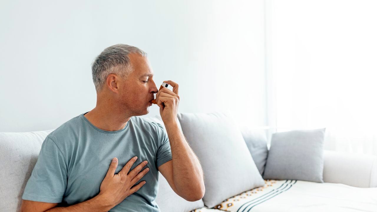 Hombre maduro, el tratamiento del asma con inhalador en casa