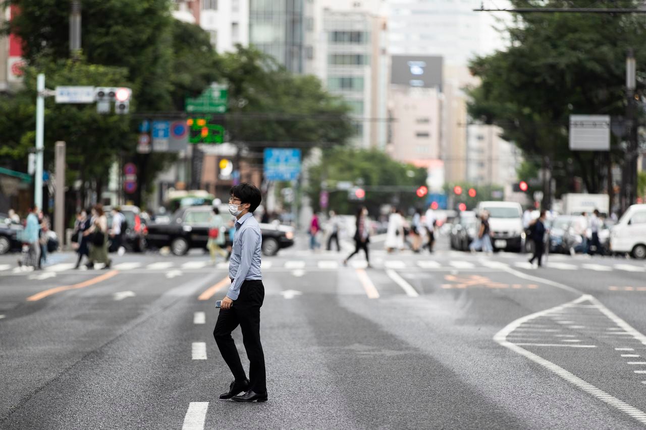 Un hombre con mascarilla cruza una calle en el popular barrio comercial de Ginza, en Tokio, el 21 de mayo de 2021. (AP Foto/Hiro Komae)