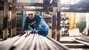 Trabajadora de una fábrica de acero en el trabajo moviendo postes de acero