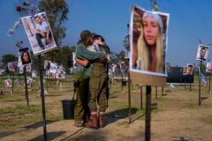 Soldados israelíes se abrazan junto a fotografías de personas asesinadas y tomadas cautivas por militantes de Hamas durante su violento ataque en el festival de música Nova en el sur de Israel