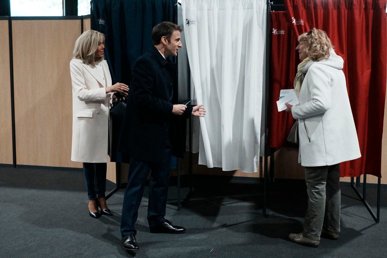 El presidente de Francia y candidato presidencial del partido LREM, Emmanuel Macron (centro), junto a su esposa Brigitte Macron (izquierda), habla con un residente antes de votar en la primera ronda de las elecciones presidenciales de Francia en un colegio electoral en Le Touquet, en el norte de Francia, el 10 de abril. , 2022. (Foto de Thibault Camus / POOL / AFP)