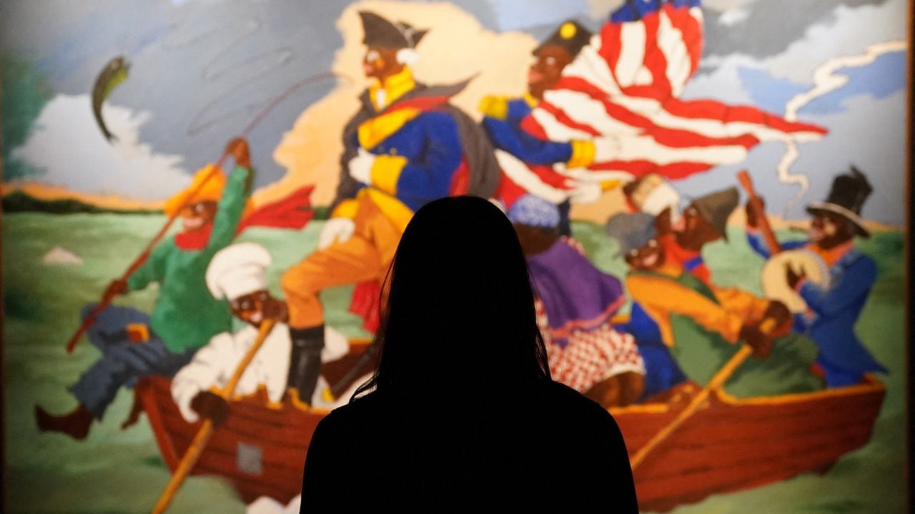 (FILES) In this file photo taken on May 04, 2021, woman poses in front of Robert Colescott's "George Washington Carver Crossing the Delaware: Page from an American History Textbook" during a press preview for Sotheby�s Impressionist & Modern Art Evening Sale Live Auction: May 12, 2021, in New York. - Black artists are represented like never before at New York's spring sales next week after years of being overlooked and underappreciated, with several expected to set new records for their works. American-born Jean-Michel Basquiat, of Haitian and Puerto Rican descent, becomes the first Black painter to headline both Christie's and Sotheby's main auctions, on May 11 and 12, 2021, respectively.