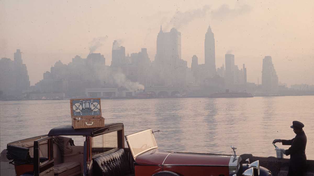A chauffeur unpacks a picnic hamper from a Rolls Royce, against the New York skyline.  (Photo by Slim Aarons/Getty Images)
