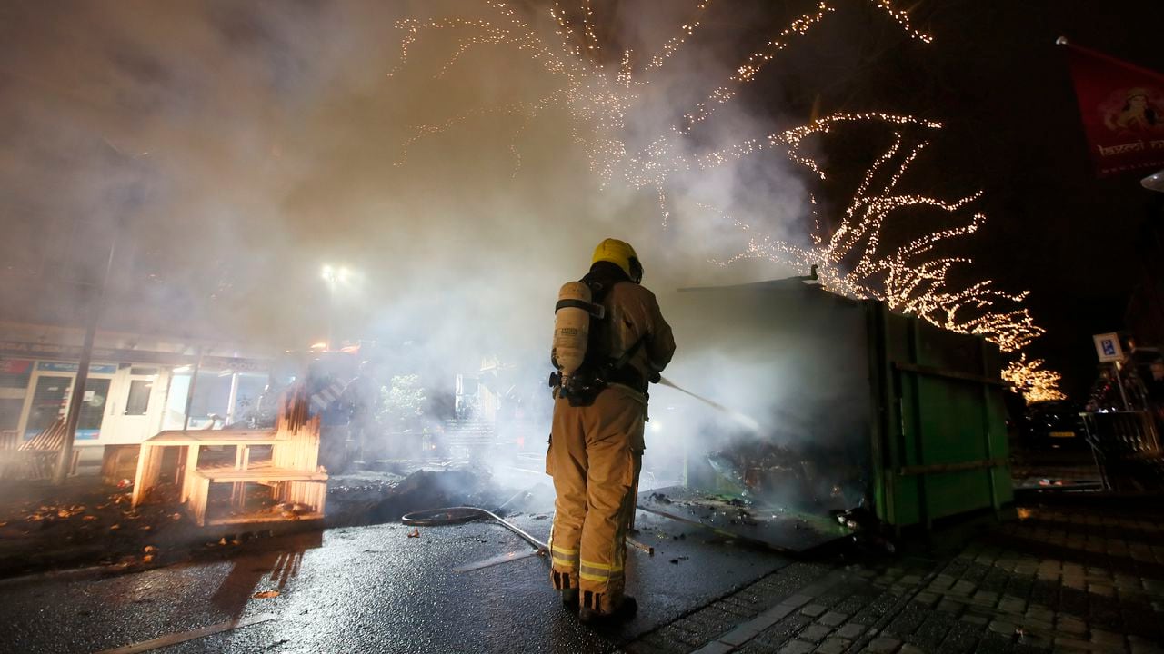A firefighter extinguishes a a container that was set alight during protests against a nation-wide curfew in Rotterdam, Netherlands, Monday, Jan. 25, 2021. The Netherlands Saturday entered its toughest phase of anti-coronavirus restrictions to date, imposing a nationwide night-time curfew from 9 p.m. until 4:30 a.m. in a bid to control the COVID-19 infection rate. (AP Photo/Peter Dejong)