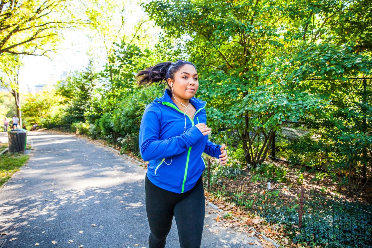Plus size woman running in Central Park, New York during a beautiful day.