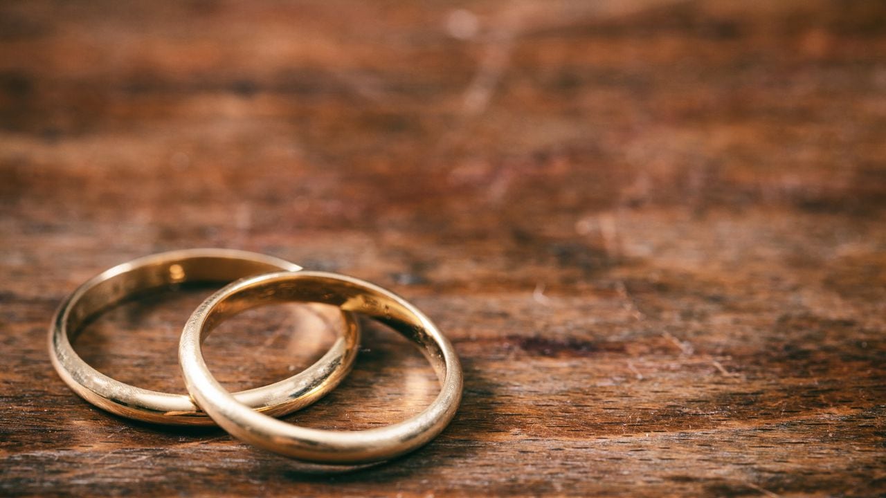 Un par de anillos de bodas de oro sobre fondo de madera, espacio de copia