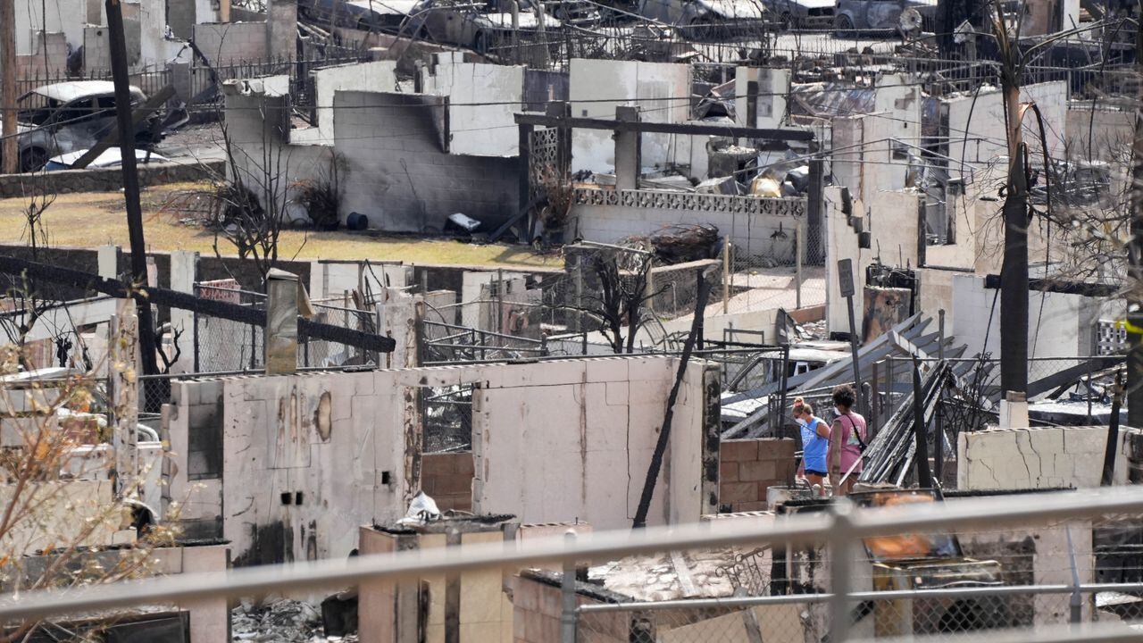 Dos personas examinan una casa quemada después de que un infierno destruyera gran parte de la histórica ciudad turística de Lahaina, Hawái, EE. UU