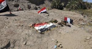 Vista de fosas clandestinas de la supuesta tumba de milicianos del Estado Islámico (EI) en la base de Spiker, junto a la bandera de Irak. (Efe)