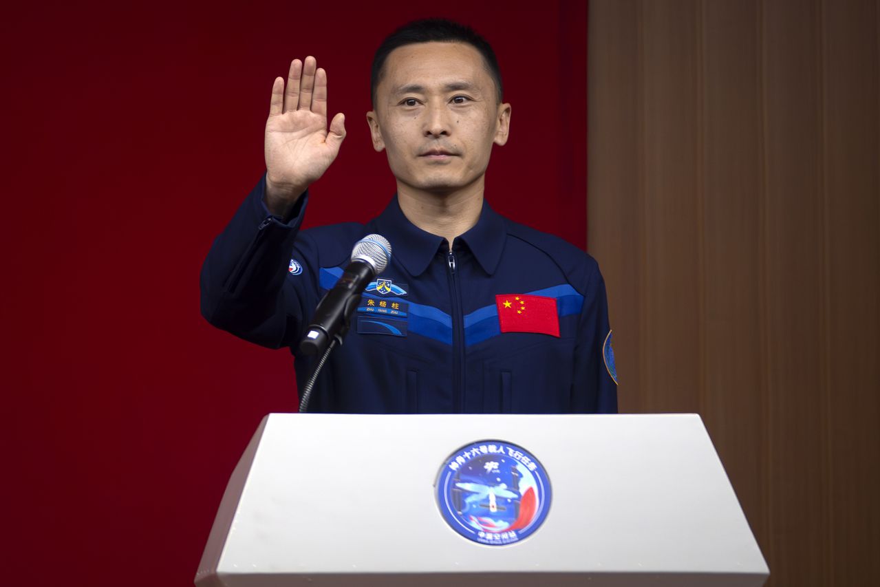 Zhu Yangzhu, un astronauta chino de la próxima misión Shenzhou-16 saluda mientras se para detrás de un vidrio durante una reunión con la prensa en el Centro de Lanzamiento de Satélites de Jiuquan en el noroeste de China el lunes 29 de mayo de 2023